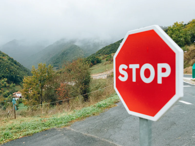 Mountain road with a stop sign illustrating the need for clear protective actions and controlled access