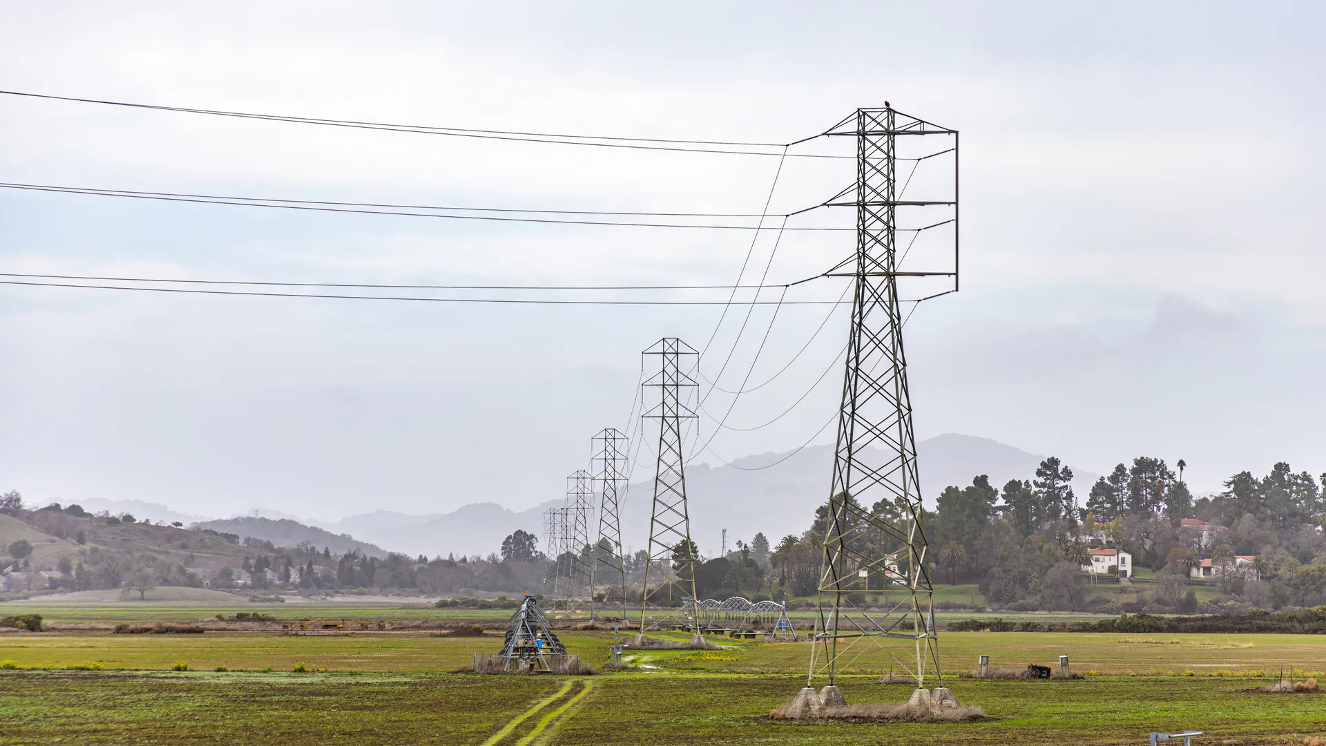 Transmission towers crossing open terrain where a drone inspection must preserve asset identity and flight geometry